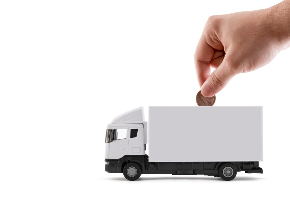 une main mettant une pièce de monnaie dans un camion de livraison