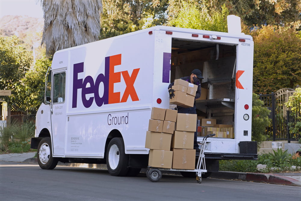 Camion de livraison FedEx avec du personnel déchargeant des boîtes d'expédition.