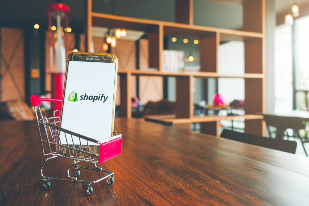 a cell phone with the Shopify logo on the screen in a shopping cart