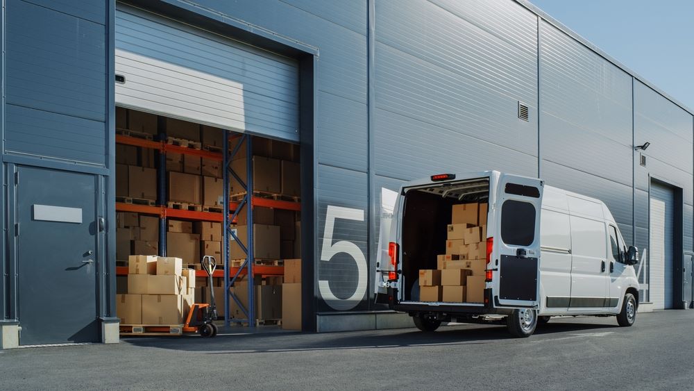 A delivery van filled with packages outside a warehouse