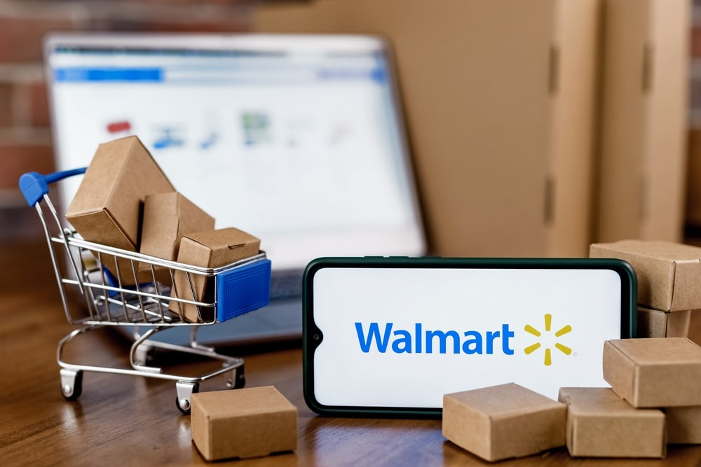a phone with the Walmart on screen, with a shopping cart and boxes on a table