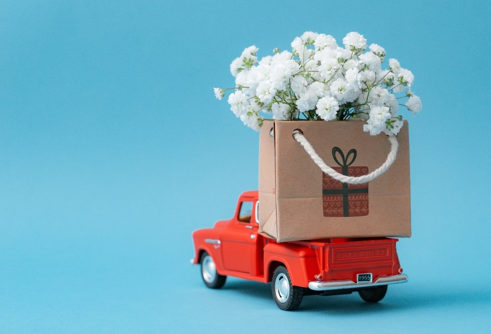 a red toy truck with a box of flowers on the back