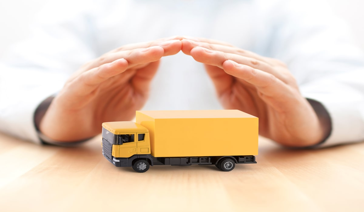 A person covering a yellow toy truck with their hands.