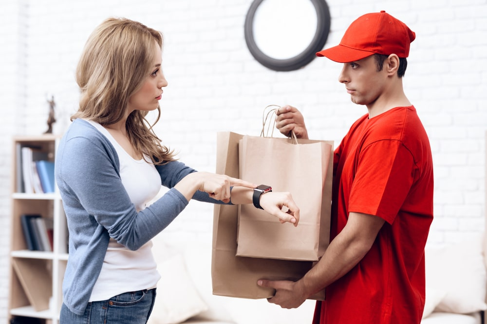 A man holding a shopping bag and a woman pointing finger to her watch