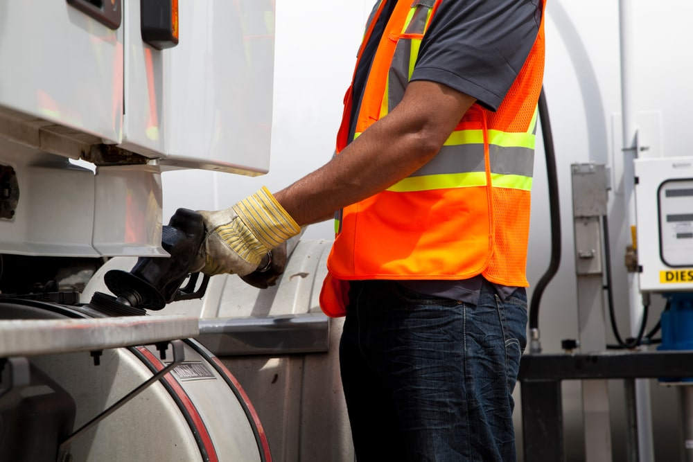 A worker pumps gas into a vehicle's tank.