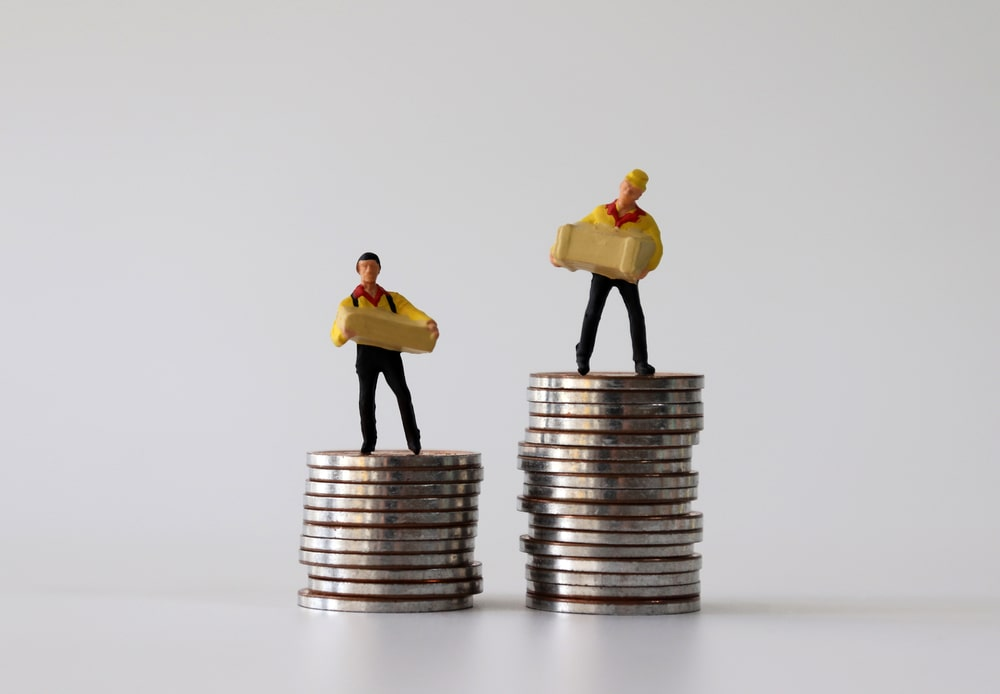 Two small toy human figures on top of coins
