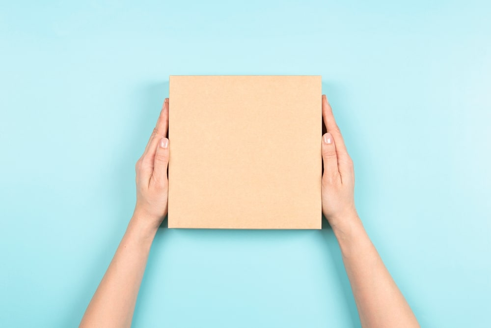 two hands holding a box on blue background