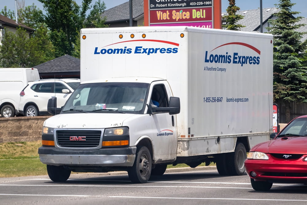 a white Loomis Express delivery truck parked on the side of a road