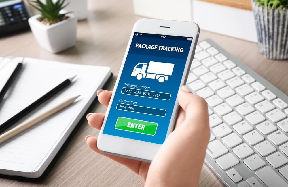 A hand holding a phone with the package tracking site