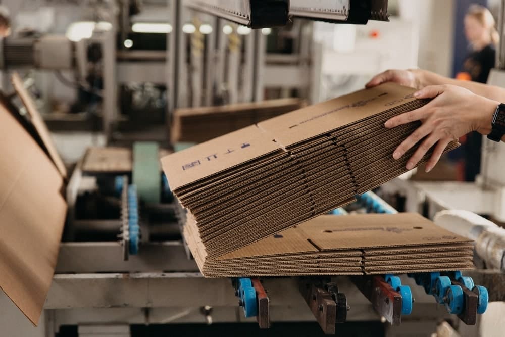 A hand holding stacks of folded carton boxes