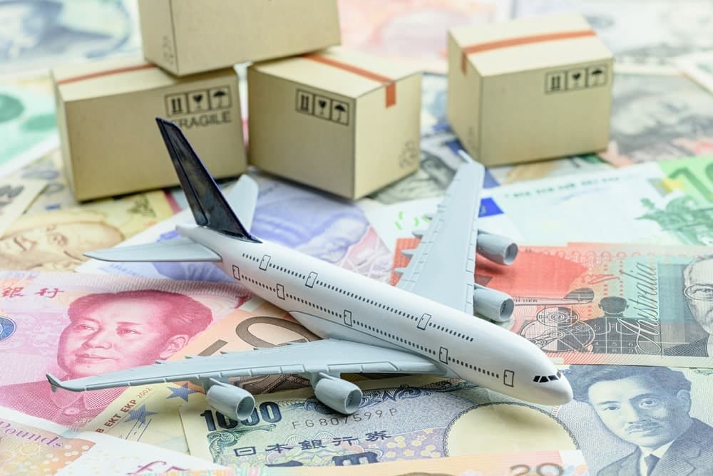 A toy airplane on top of different paper bills with stacks of boxes at the back