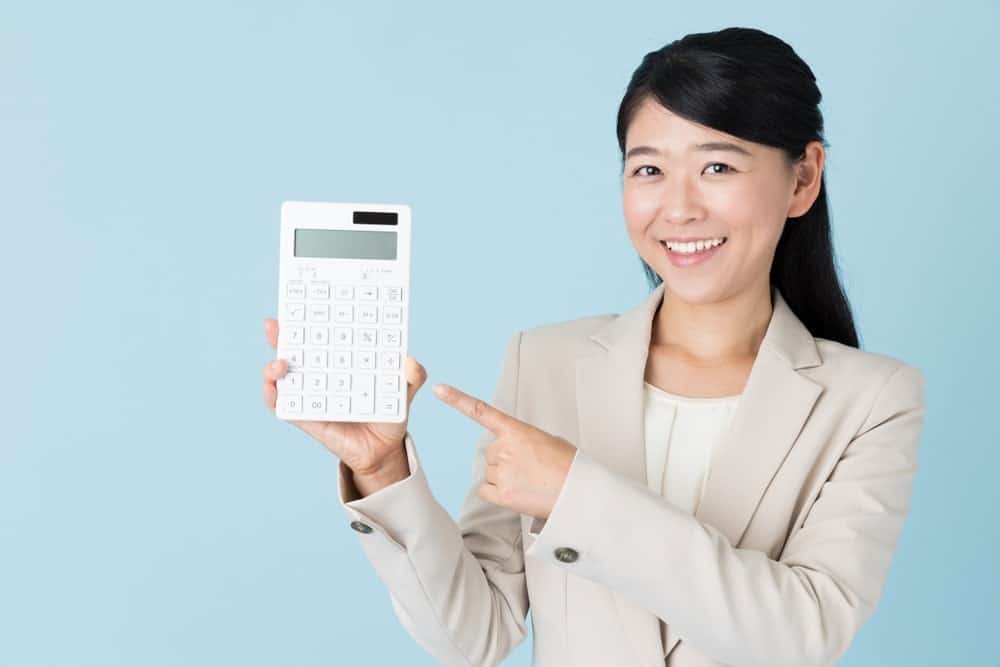 An Asian woman holding a white calculator