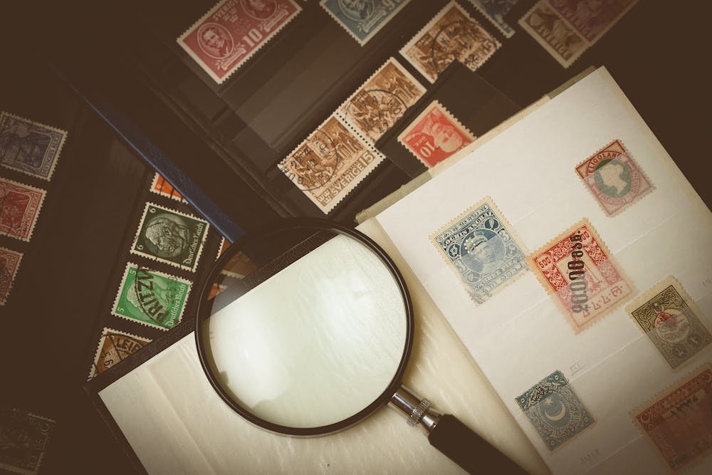 different stamps pasted on a notebook with a magnifying glass on top