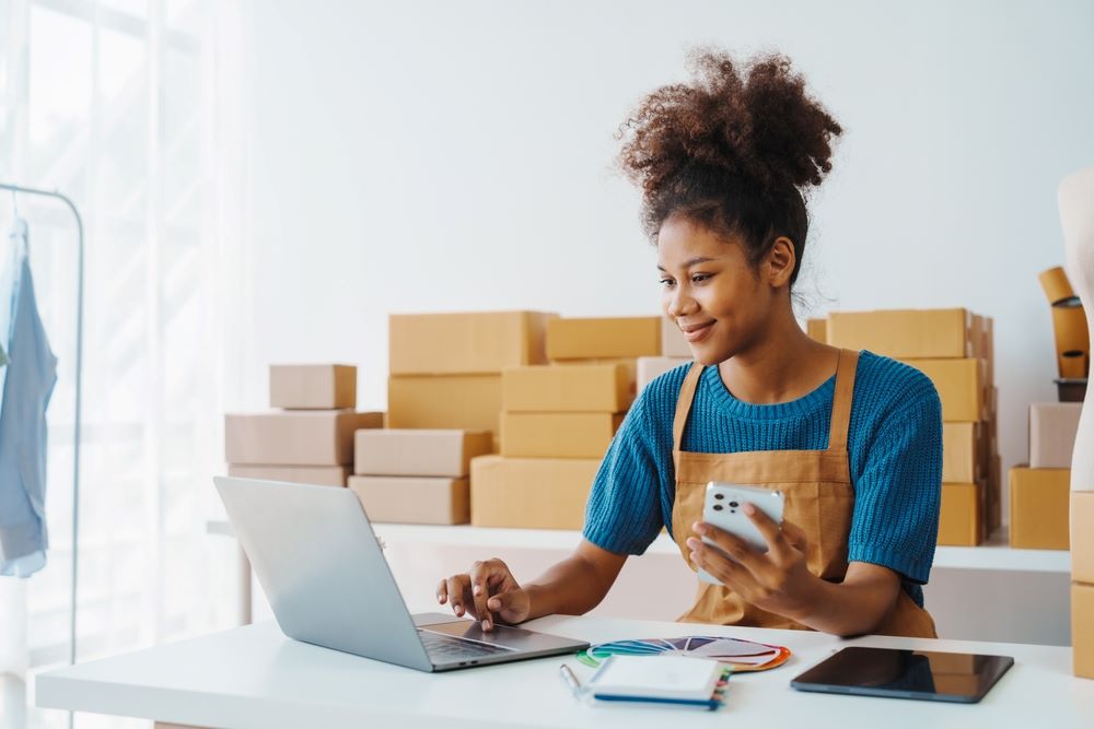 A business woman using a phone and a laptop