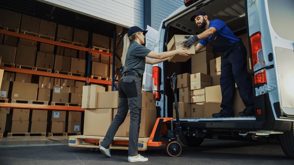 A male and female loading packages inside a delivery vehicle