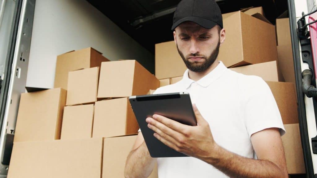 A man holding a tablet with packages behind him