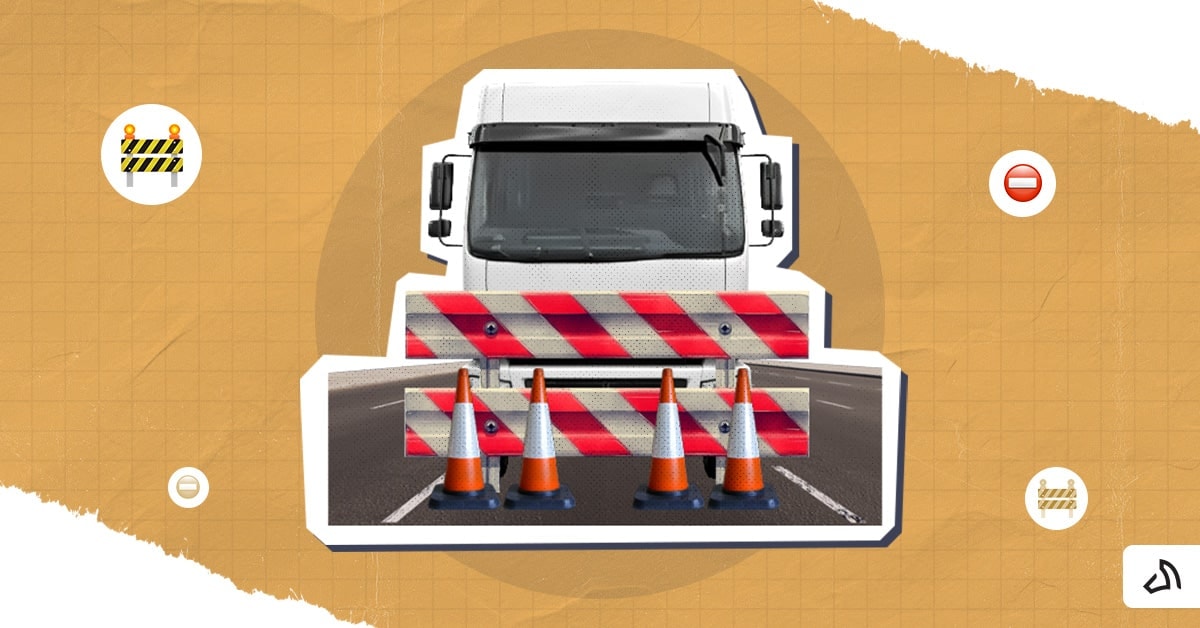 A white delivery truck stopped by traffic cones and a barrier. 